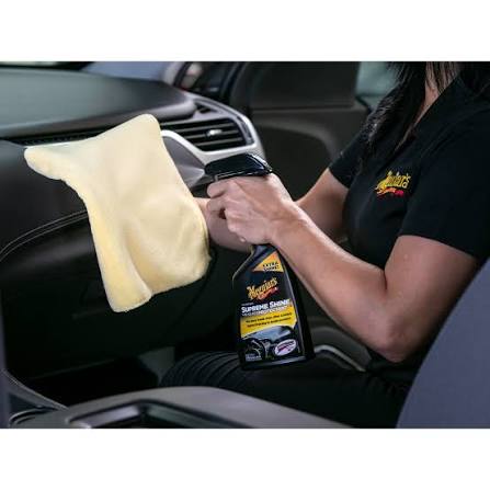 Person cleaning car interior with a cloth and bottle of Meguiar's Speed Shine