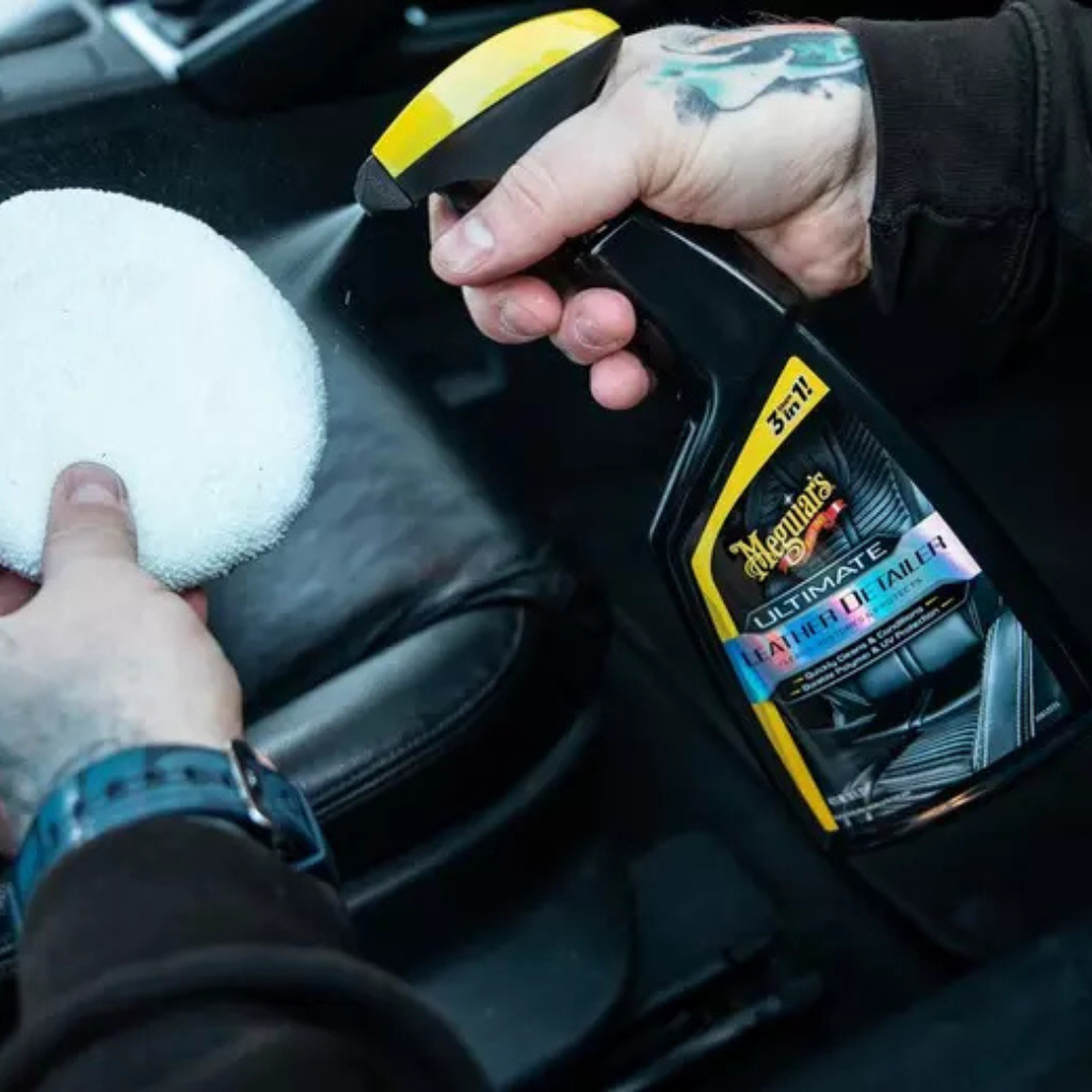 Person holding a car detailing product and a polisher inside a vehicle.