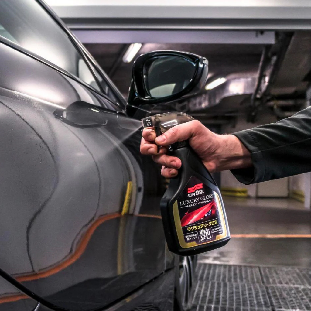 Person holding a car care product spray can near a car in a garage.